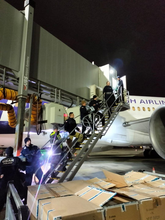 Strażacy po dotarciu do Warszawy ręcznie pakują niezbędny sprzęt na pokład samolotu Boeing 787 Dreamliner użyczonego przez PLL Lot
