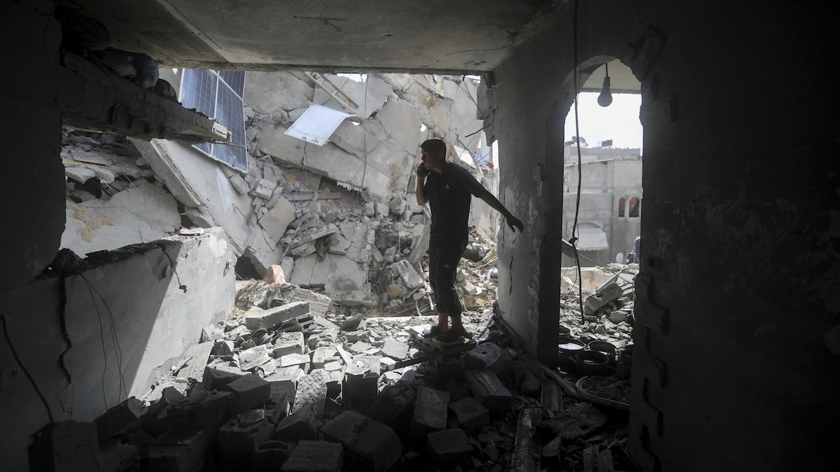 Palestínčania sa pozerajú na ruiny po izraelskom útoku na obytnú budovu v Rafahu