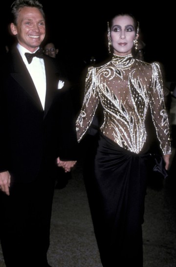 1985 Cher - Van valami annyira sikkes és különleges a 90-es évekbeli Cher megjelenésben. Az énekesnő egy merész, áttetsző, gyöngyökkel díszített ruhát viselt, amelyet Bob Mackie tervezett. Az ikonikus darab tökéletesen tükrözte Cher extravagáns és színpadi stílusát.