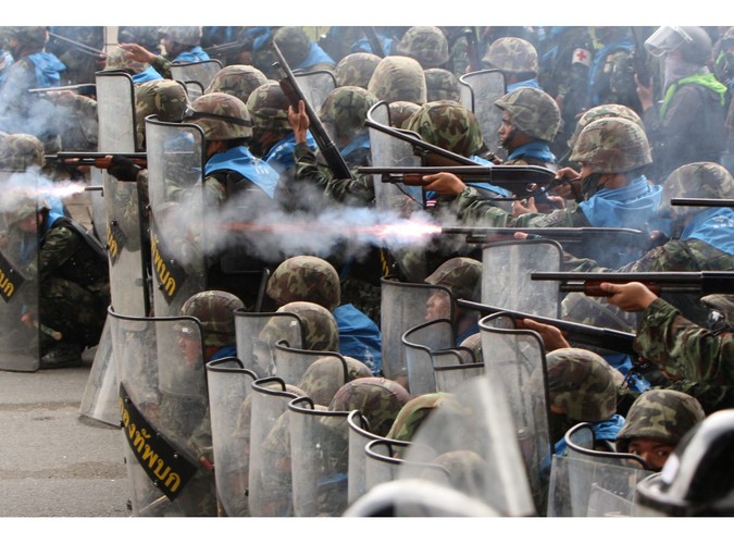 Tajscy żołnierze strzelają gumowymi kulami w kierunku demonstrantów protestujących przeciwko polityce rządu w Bangkoku 28 kwietnia 2010