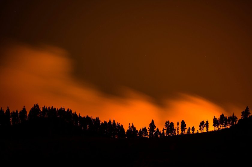 Flames and smoke from a forest fire are seen in the village of Valleseco