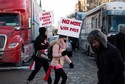 Ludzie spacerują przed ciężarówkami zaparkowanymi na Wellington Street, dołączając do wiecu przeciwko ograniczeniom COVID-19 na Parliament Hill.