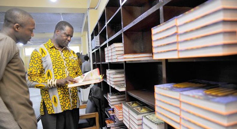 Dr Yaw Osei Adutwum, Deputy Minister in Charge of General Education glancing through a book at the Central Library in Accra with him is Mr Hayford Siaw,the Ag Chief Executive Officer of the GLA.