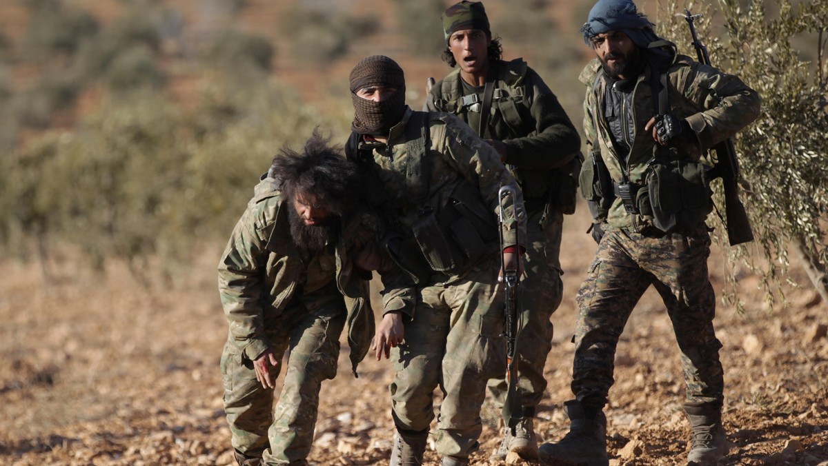 Rebel fighters help a fellow fighter, who was injured during an offensive against Islamic State fighters, on the outskirts of the northern Syrian town of al-Bab