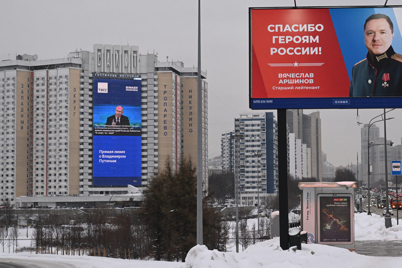 Ekran na fasadzie budynku mieszkalnego w Moskwie transmitujący konferencję prasową prezydenta Rosji Władimira Putina oraz billboard z napisem "Dzięki bohaterom Rosji", 14 grudnia 2023 r.