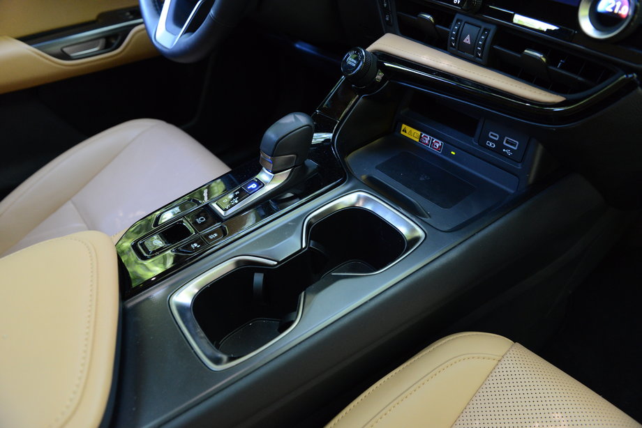 Lexus NX 350h z punktu widzenia kierowcy ma bezstopniową skrzynię automatyczną. Niewielki wybierak służy do ustawiania trybu jazdy. Obok niego pozostało jeszcze miejsce na poręczny schowek i wnękę na kubki z napojami.