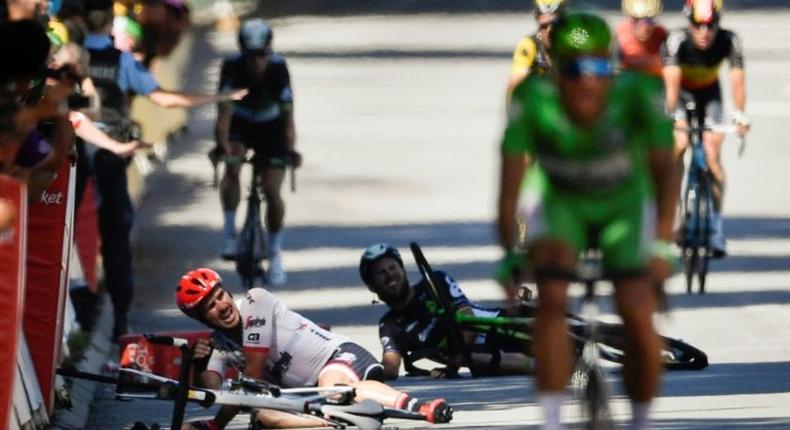 Germany's John Degenkolb (L) and Great Britain's Mark Cavendish (2ndL) lie on the ground after falling near the finish line at the end of the fourth stage of the 104th edition of the Tour de France July 4, 2017 between Mondorf-les-Bains and Vittel