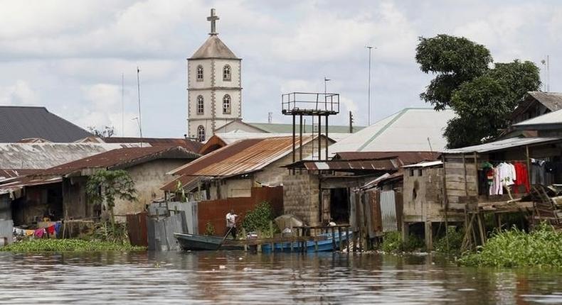 A church minaret is seen behind houses built near the banks of the Nun River on the outskirts of the Bayelsa state capital, Yenagoa, in Nigeria's delta region October 8, 2015. 