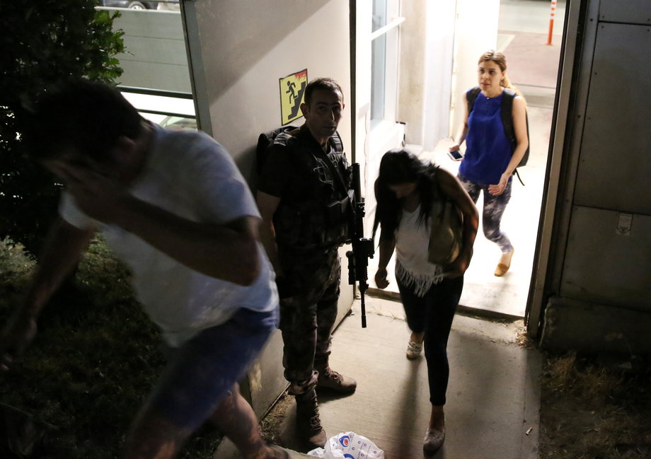 An armed security man escorts people from a car park at Istanbul Ataturk Airport after a blast on June 28.