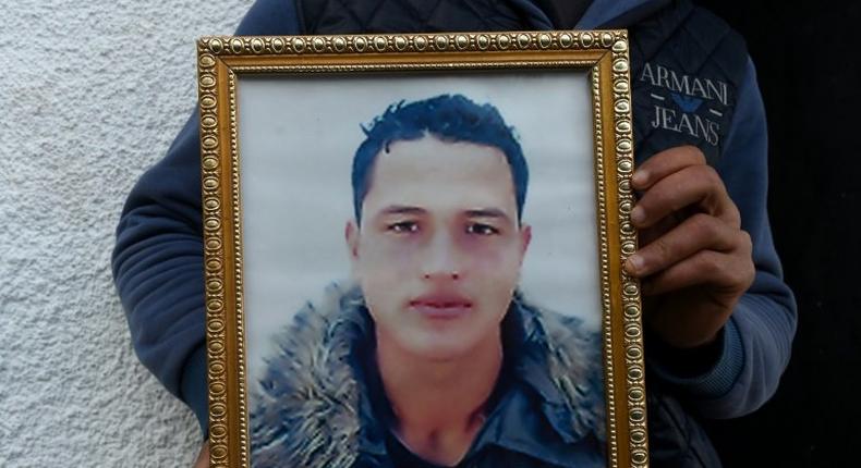 Walid Amri (back), the brother of 24-year-old Anis Amri, the prime suspect in Berlin's deadly truck attack, poses with a portrait of his brother in front of the family house in the town of Oueslatia, in Tunisia