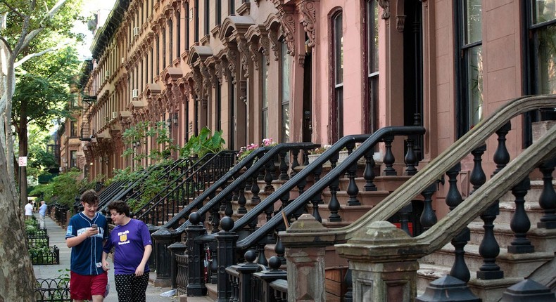 People walk past brownstone townhouses in the Fort Greene neighborhood on June 24, 2016 in the Brooklyn borough of New York City.Drew Angerer/Getty Images