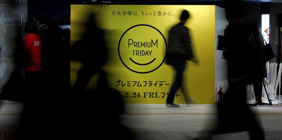 People walk past a sign advertising the Premium Friday campaign.