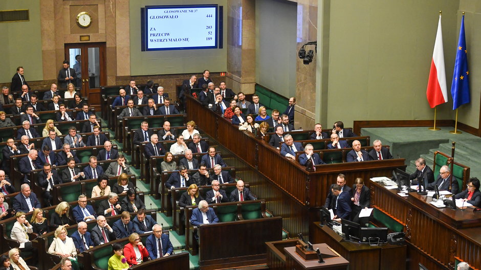 Posłowie na sali obrad Sejmu. W tle tablica z wynikiem głosowania nad projektem nowelizacji ustawy o SN