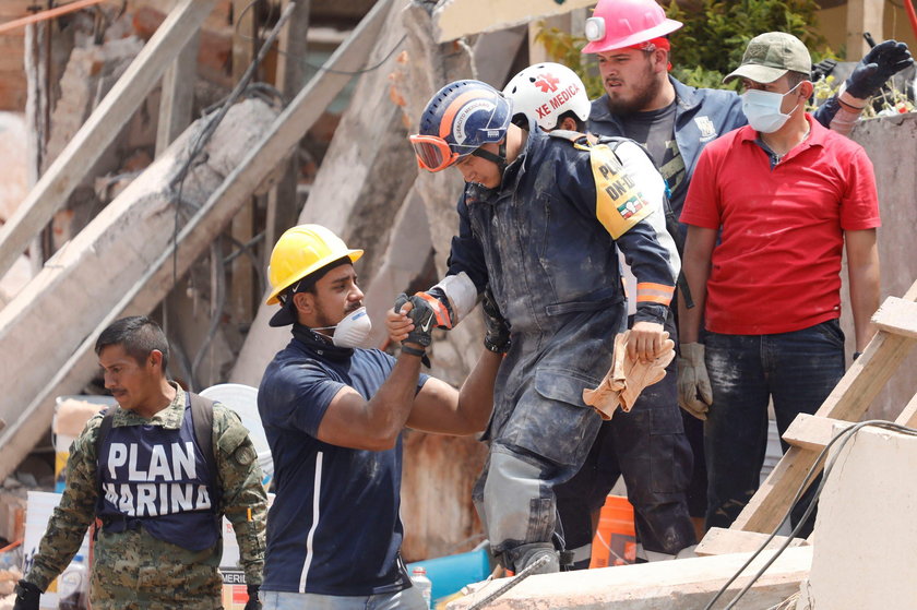 A rescue worker is helped during the search for students at Enrique Rebsamen school after an earthqu