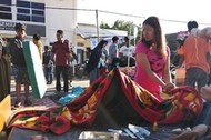 A woman stands near an injured person outside of a hospital after an earthquake hit Sembalun Selong village in Lombok Timur