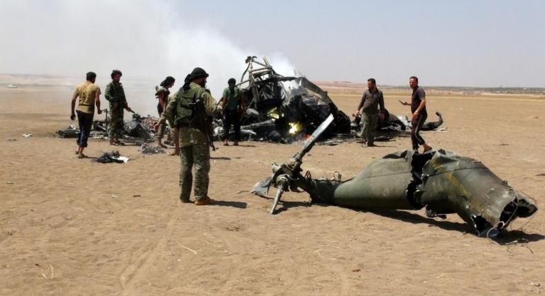 Syrian rebels look at the wreckage of a Russian military transport helicopter shot down between Idlib province, and neighbouring Aleppo