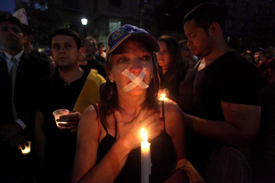 A Venezuelan woman living in Chile, whose mouth is taped, takes part in a protest against the visit of Venezuela's President Nicolas Maduro, in Santiago, March 10, 2014.