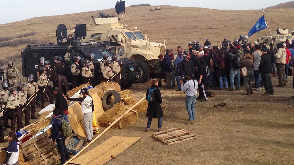 A line of police move towards a roadblock and encampment of Native American and environmental protesters near an oil pipeline construction site, near the town of Cannon Ball