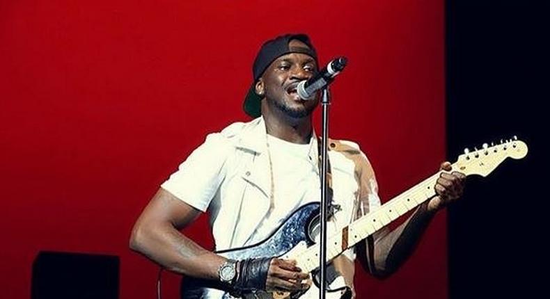 Peter Okoye playing the guitar on stage