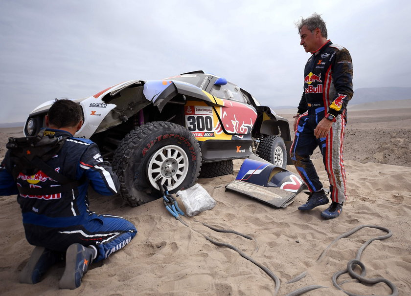 Driver Carlos Sainz, of Spain, and co-driver Lucas Cruz, of Spain, work on their Mini after it broke