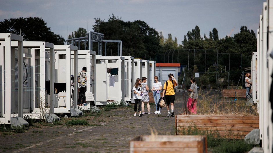 Młodzi migranci zbierają się na osiedlu domów kontenerowych na dawnym lotnisku Tempelhof w Berlinie, Niemcy, 8 sierpnia 2022 r.