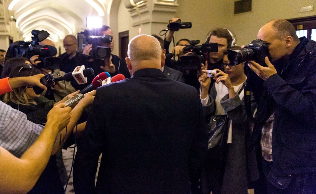 Oskarżony Piotr R. (tyłem) rozmawia z dziennikarzami na korytarzu sądowym