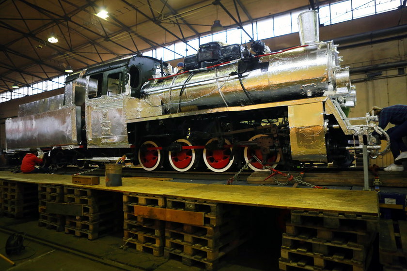 Oklejona folią aluminiową lokomotywa stanie przed dworcem Łódź Fabryczna