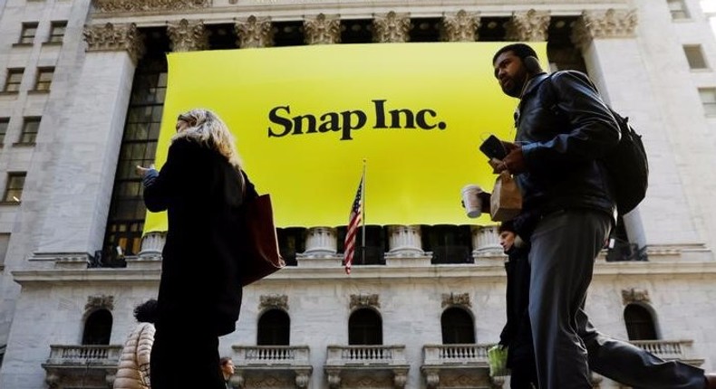 Pedestrians walk past the front of the New York Stock Exchange (NYSE) with a Snap Inc. logo hung on the front of it shortly before the company's IPO in New York.