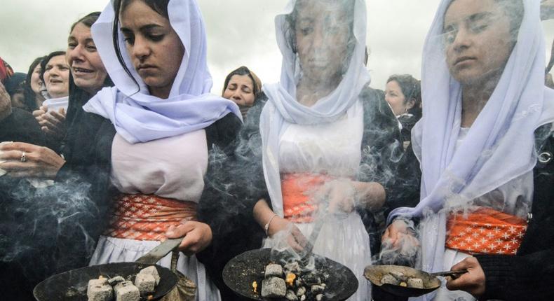 Members of the Yazidi minority take part in a ceremony during the exhumation of a mass grave of victims of the Islamic State group in northern Iraq