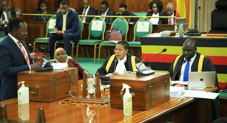 Wilson Kajwengye (L) speaking during the Committee of the Whole House on Tuesday, April 23. Speaker, Anita Among (C) and a staff of Parliament (R) are at the Clerk’s Table