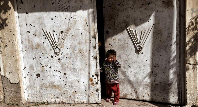 An Iraqi child stands outside a door in west Mosul, northern Iraq, on March 7, 2017, as Iraqi forces battle Islamic State (IS) group fighters to further advance inside the city