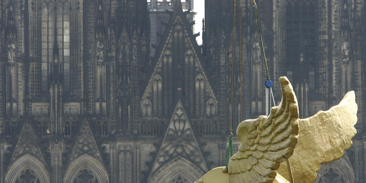 Workers install the sculpture 'Golden Bird' by German artist HA Schult in front of the cathedral in Cologne May 2, 2005. The sculpture has been on show at Cologne museum sine1991 and after restoration is on show outside the cathedral.