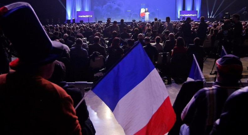 A supporter holds a French national flag as Marine Le Pen, French National Front (FN) political party leader and candidate for French 2017 presidential election, delivers a speech during a political rally in Metz, France, March 18, 2017.