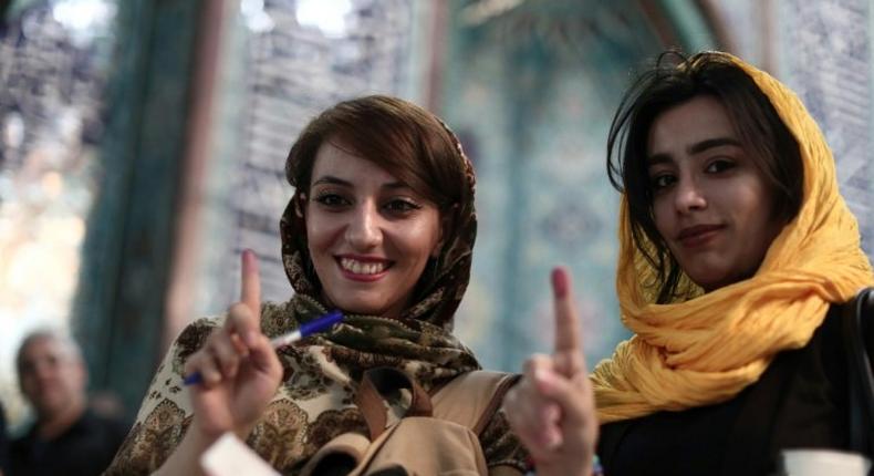 Iranian women show their ink-stained fingers after voting in presidential elections at a polling station in Tehran on May 19, 2017