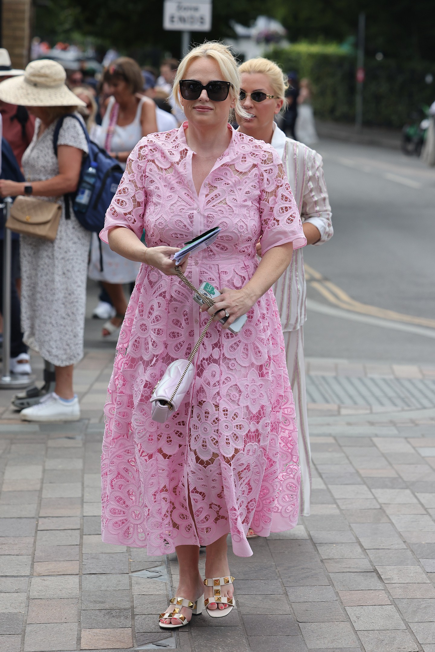 Rebel Wilson rózsaszín csipkeruhája és hozzá illő Gucci táskája tökéletes választás volt a wimbledoni torna második napjára. A túlméretezett napszemüveg és a szegecses Valentino szandál tovább fokozta a ruha kerti parti hangulatát.