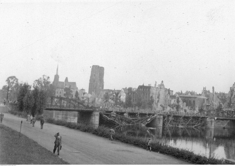 Wrocław, panorama Ostrowa Tumskiego. Na pierwszym planie bulwar, Odra i uszkodzony most Lessinga (widoczne dwa zniszczone przęsła). W głębi zabudowa Ostrowa Tumskiego, m.in. archikatedra św. Jana Chrzciciela, kościół św. Krzyża i św. Bartłomieja (z lewej). Widoczne zniszczenia wojenne, 1945-1947 r.