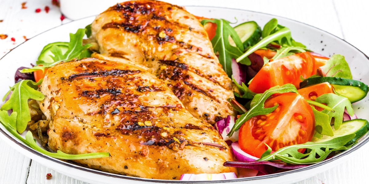 Grilled chicken breast. Fried chicken fillet and fresh vegetable salad of tomatoes, cucumbers and ar