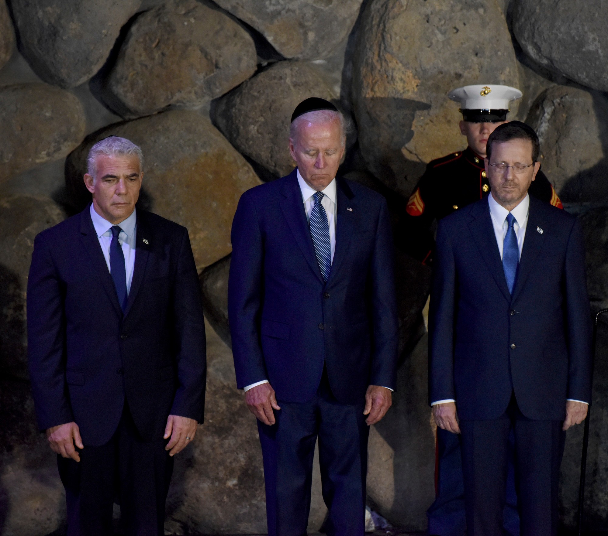 Americký prezident Joe Biden  (uprostred) stojí s izraelským premiérom Yairom Lapidom (vľavo) a izraelským prezidentom Isaacom Herzogom (vpravo) v Sieni spomienok počas ich návštevy pamätníka holokaustu Jad Vašem v Jeruzaleme.