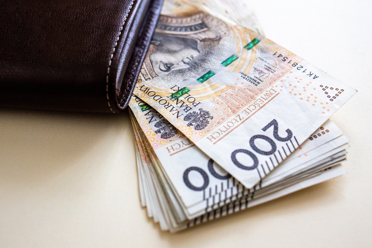 Brązowy portfel z którego wystaje plik polskich banknotów o nominale 200 złotych.