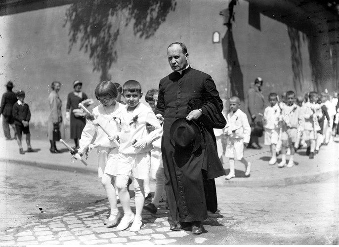 Ksiądz z dziećmi w strojach komunijnych idący ulicami Krakowa. fot. Koncern Ilustrowany Kurier Codzienny - Archiwum Ilustracji, 1933 r.