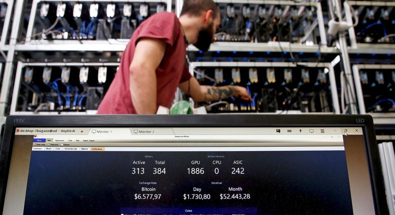 A bitcoin-mining computer and a screen showing bitcoin exchange rates at Bitminer Factory in Florence, Italy.