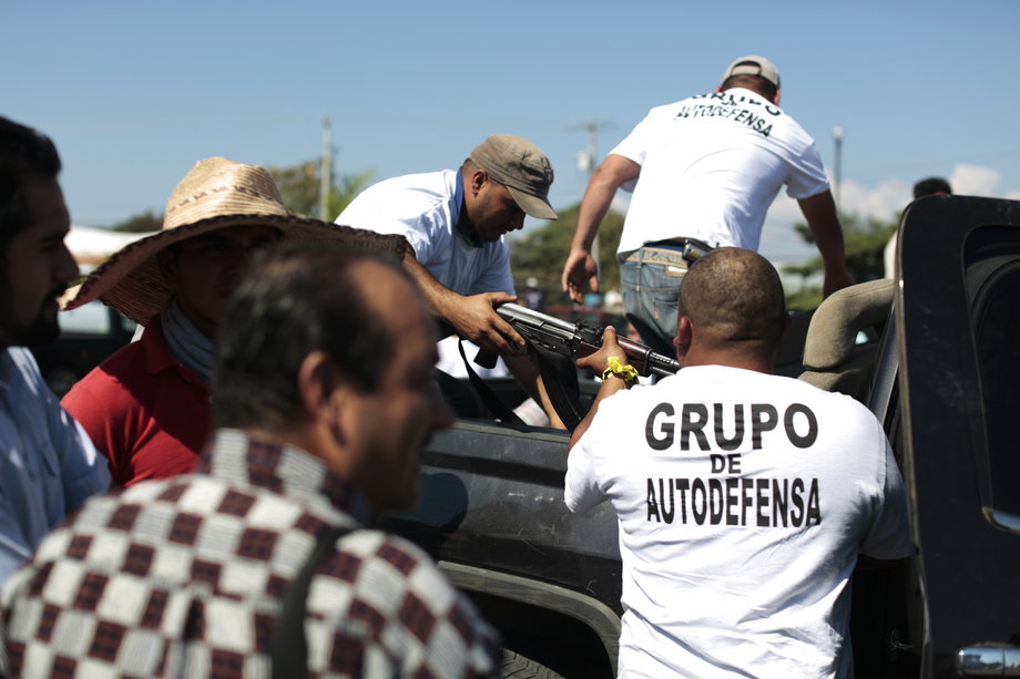 Vigilantes (in white shirts) pass a weapon into the cabin of a pick up truck in Nueva Italia, Michoacan, January 14, 2014.