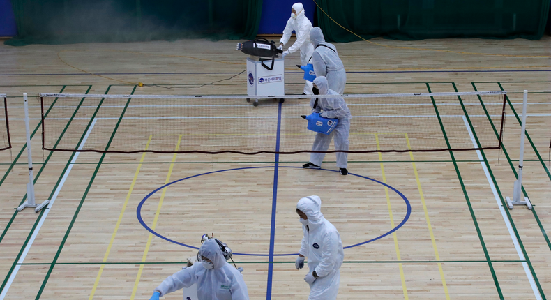 In this Feb. 25, 2020, file photo, workers in protective suits spray disinfectant as a precaution against the COVID-19 at an indoor gymnasium in Seoul, South Korea. As the coronavirus spreads around the world, many events that normally would draw large numbers of people are being canceled or played without fans. (AP Photo/Lee Jin-man, File)