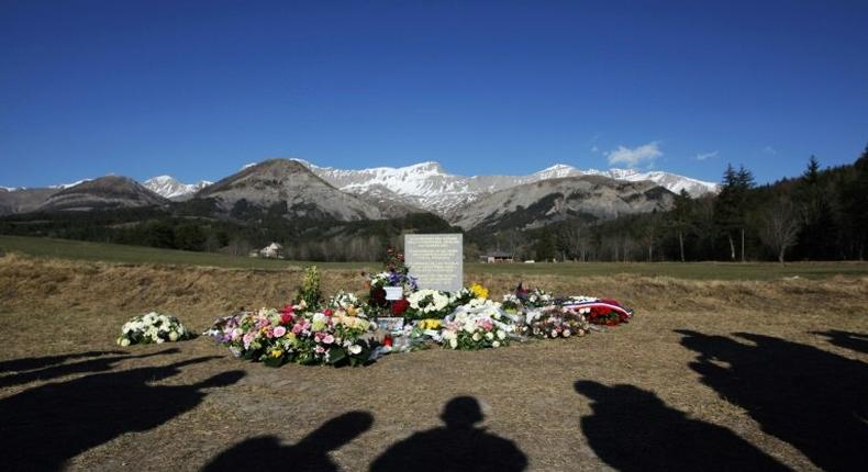 This file photo taken on April 6, 2015 shows people's shadows as they stand near a stela commemorating the victims of the March 24 Germanwings Airbus A320 crash in the village of Le Vernet, southeastern France, after a ceremony with victims' relatives.