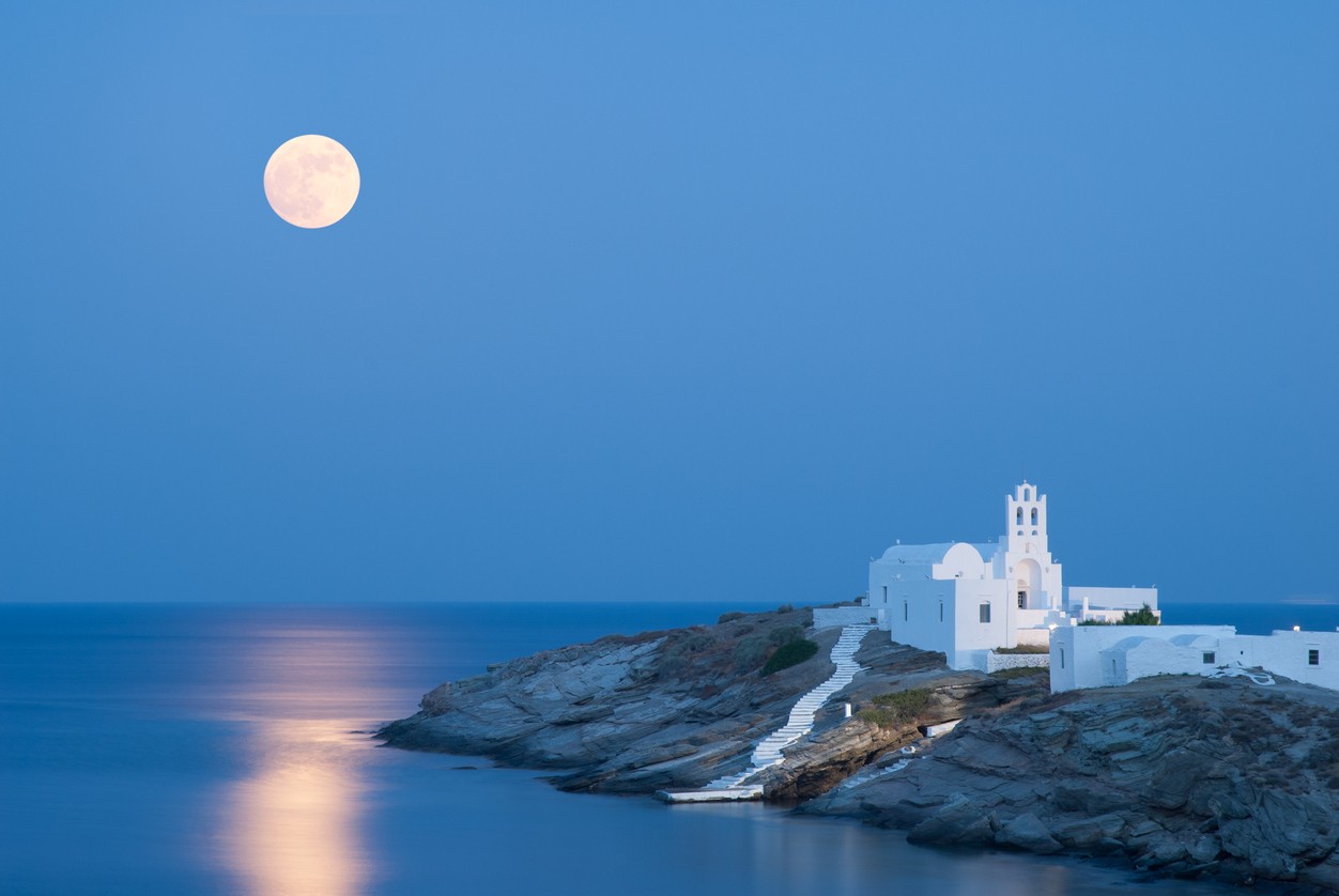 Letný záber ostrova Sifnos s úplňkom a jeho odrazom na Egejskom mori.