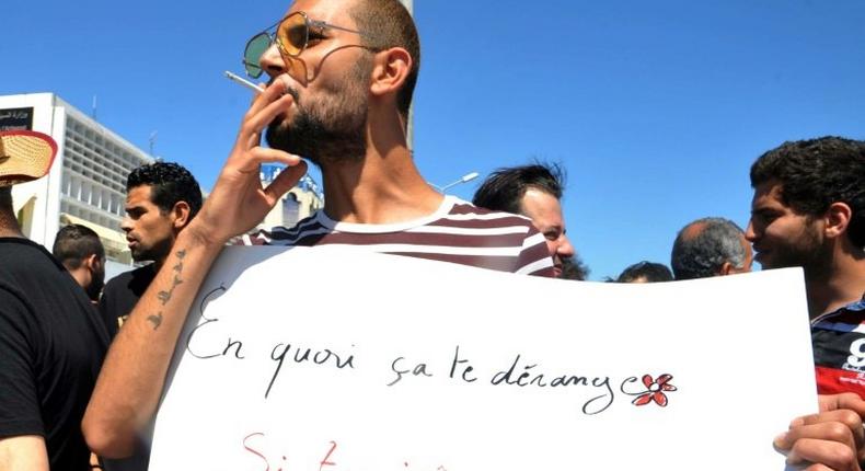 A protester in Tunis openly smokes a cigarette and holds a placard reading in French Why does it bother you if you fast and I eat? during Ramadan on June 11, 2017