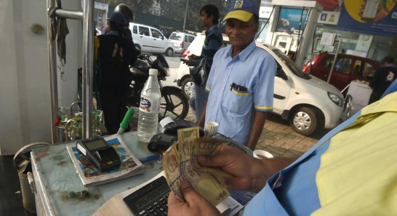 An Indian customer pays for fuel with old 500 rupee notes at a petrol station in New Delhi on the last day on which the old currency can be used to purchase fuel