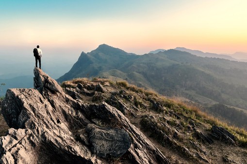 businessman hike on the peak of rocks mountain at sunset