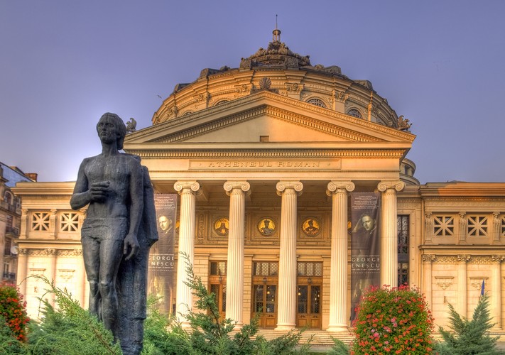 <strong>Bukareszt</strong>
<br></br>
Stolica i największe miasto. Do miejsc, które warto zobaczyć w Bukareszcie, należy z pewnością Ateneum (Ateneul Român), które jest jednym z lepszych dzieł tutejszej architektury. W wielu punktach miasta natknąć się można na ocalałe zabytki sakralne - najczęściej cerkwie, które w epoce komunistycznej podlegały planowemu niszczeniu. Komunizm pozostawił po sobie wiele budowli w stylu socrealizmu. Łatwo je dostrzec spacerując po centrum miasta. 
<br></br>
Szczególną uwagę warto zwrócić na Plac Rewolucji (Piața Revoluției) - najważniejsze miejsce stolicy. To tutaj kończył się w Rumunii komunizm, czyli reżim Ceaușescu. Zobaczymy tu zarówno piękny Pałac Królewski (dziś Muzeum Sztuk Pięknych), jak i dawny dom partii komunistycznej, okazałą bibliotekę i Cerkiew Kretzulescu.
<br></br>
Wśród wielu spacerów po mieście warto jeden z nich zaplanować po terenie Parku Herăstrău. Największy w Bukareszcie, założony jeszcze przed wojną, ma powierzchnię ponad 100 hektarów. Będąc w Parku Herăstrău warto zobaczyć rozległy skansen - czyli Muzeum Wsi (Muzeul Național al Satului „Dimitrie Gusti”). W jednym miejscu można tu zobaczyć, jak przez wieki toczyło się wiejskie życie poza dużymi miastami.
<br></br>