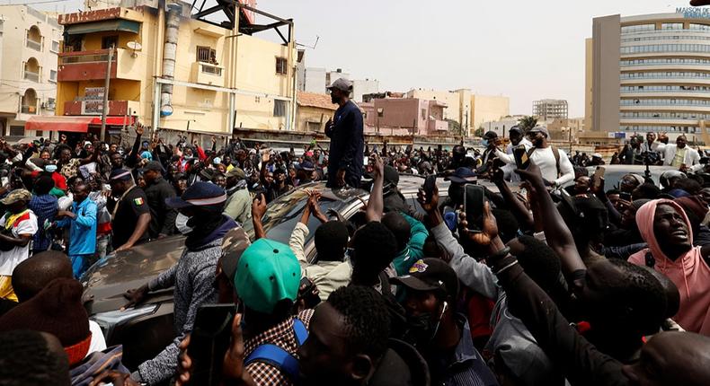 Le chef de l’opposition sénégalaise, Ousmane Sonko, sur le toit d’une voiture après son audience au tribunal à Dakar, le 16 février 2023. © ZOHRA BENSEMRA/REUTERS